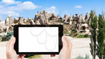 travel concept - tourist photographs of ancient monastic settlement near Goreme town in Cappadocia in spring in Turkey on smartphone with empty cutout screen with blank place for advertising