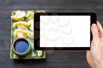 travel concept - tourist photographs of Chinese cuisine dish of Dumplings with three fillings (shrimp, egg, greens) on plate on smartphone with empty cutout screen with blank place for advertising