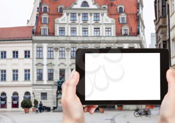 travel concept - tourist photographs of Fuggerplatz square with statue of Hans Jakob Fugger in Augsburg town in Germany on smartphone with empty cutout screen with blank place for advertising