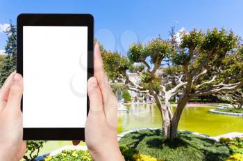 travel concept - tourist photographs of fountain in public park of Dolmabahce Palace in Istanbul city in Turkey on smartphone with empty cutout screen with blank place for advertising