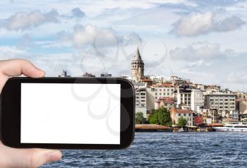 travel concept - tourist photographs of Galata Tower in Karakoy District in Istanbul city in Turkey on smartphone with empty cutout screen with blank place for advertising