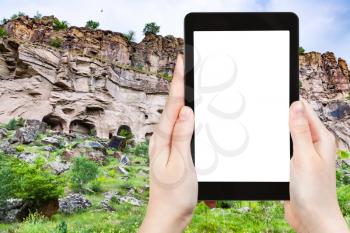 travel concept - tourist photographs of rocks caves in Ihlara Valley of Aksaray Province in Cappadocia in spring in Turkey on smartphone with empty cutout screen with blank place for advertising