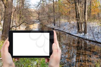 travel concept - tourist photographs of river in city park covered by the first snow in sunny october day in Moscow Russia on smartphone with empty cutout screen with blank place for advertising
