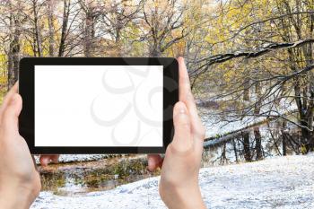 travel concept - tourist photographs of city park with river covered with the first snow in sunny autumn day in Moscow Russia on smartphone with empty cutout screen with blank place for advertising