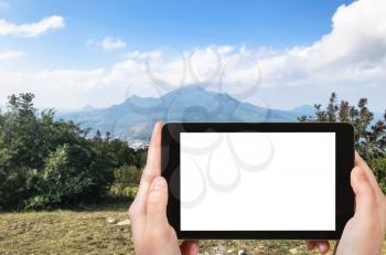 travel concept - tourist photographs of five tops of Mount Beshtau from viewpoint on top Mashuk mount in Pyatigorsk city of Russia on smartphone with cut out screen with blank place for advertising