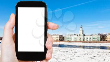 travel concept - tourist photographs of Universitetskaya Embankment with palaces on Vasilievsky Island in Saint Petersburg city on smartphone with empty cutout screen with blank place for advertising