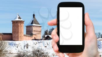 travel concept - tourist photographs of Passage Tower of Monastery of Our Savior and St Euthymius in Suzdal town in winter of Russia on smartphone with cutout screen with blank place for advertising