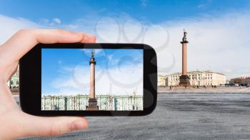 travel concept - tourist photographs Alexander Column and Winter Palace at Palace Square in Saint Petersburg city in Russia on smartphone in spring