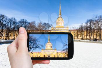 travel concept - tourist photographs of old Admiralty building from Alexander Garden in Saint Petersburg city in Russia on smartphone in spring