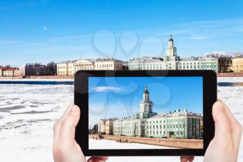 travel concept - tourist photographs of Universitetskaya Embankment with Kunstkamera and Academy of Sciences building on Vasilievsky Island in St Petersburg city in Russia on smartphone in sping