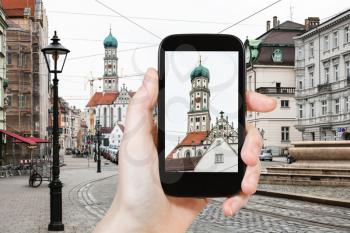 travel concept - tourist photographs of towers of St Ulrich and St Afra Church in Augsburg city in Germany on smartphone
