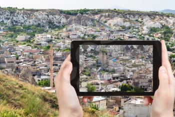 travel concept - tourist photographs of various apartment houses in Goreme town in Cappadocia on smartphone in Turkey in spring
