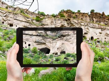 travel concept - tourist photographs of rock-cut caves in Ihlara Valley of Aksaray Province in Cappadocia on smartphone in Turkey in spring