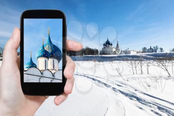 travel concept - tourist photographs of Kremlin with Chathedral of Nativity of the Virgin (Nativity of the Theotoko in Suzdal town in Russia on smartphone in winter