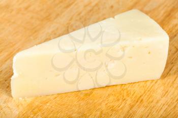 piece of local italian Pecorino Romano sheep's milk cheese on light wooden cutting board
