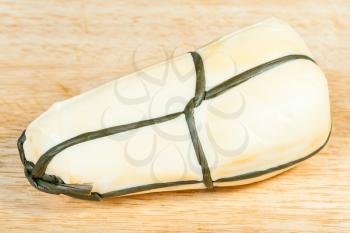 top view of local italian Provola Affumicata (smoked provola) cheese on light wooden cutting board