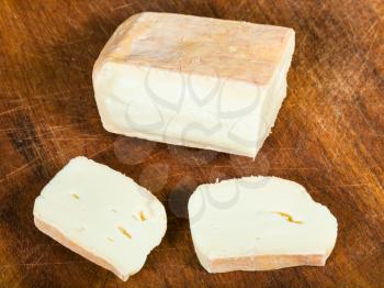 sliced local italian Taleggio cheese from cow's full milk on dark wooden cutting board