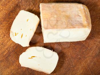 top view of sliced local italian Taleggio cheese from cow's full milk on dark wooden cutting board