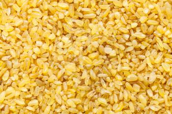 food background - bulgur (burghul), parboiled, dried and crushed wheat grains close up