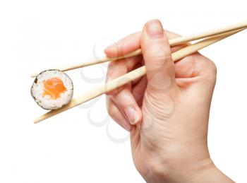 female hand with disposable chopsticks holds sake maki sushi roll with salmon fish isolated on white background