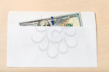 single united states one hundred-dollar bill in open mail envelope on wooden table
