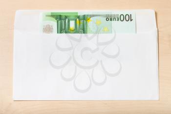 single one hundred euro note in open mail envelope on wooden table