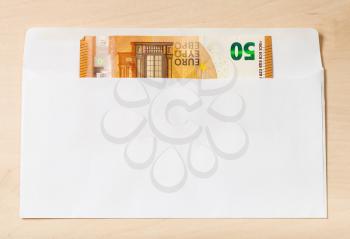 single fifty euro note in open mail envelope on wooden table