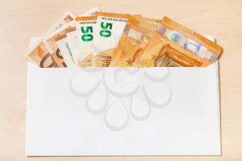 fan from several fifty euro notes in open mail envelope on wooden table