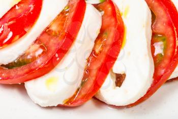italian cuisine insalata caprese (caprese salad) - sliced mozzarella cheese and tomato close up