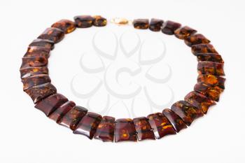 necklace from polished faceted amber flat pieces on white paper background