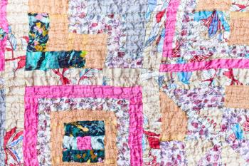 textile background - surface of patchwork scarf stitched from various silk strips and crushed pink cotton fabric