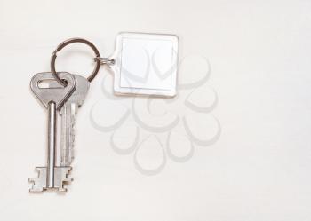 door keys on keyring with blank white keychain on pale brown table