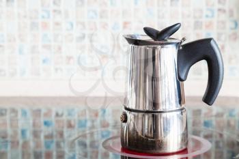 Brewing coffee with italian moka pot on ceramic electric range at home kitchen