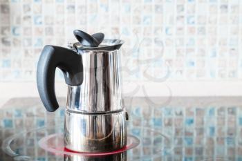 brewing coffee with pressure moka pot on ceramic electric range at home kitchen