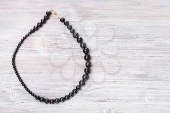 top view of jet stone necklace on gray wooden board with copyspace