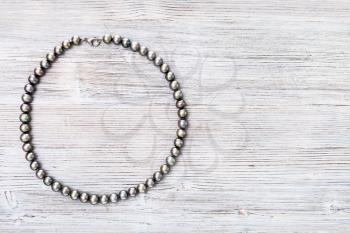 top view of natural black pearls necklace on gray wooden board with copyspace