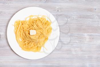 italian cuisine - top view of spaghetti al burro (pasta with butter) on white plate on gray wooden background with blank copyspace