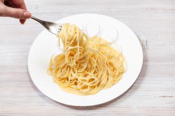 top view fork wrapped of spaghetti al burro (pasta with butter) over white plate on gray wooden table