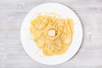 italian cuisine - top view of spaghetti al burro (pasta with butter) on white plate on gray wooden background