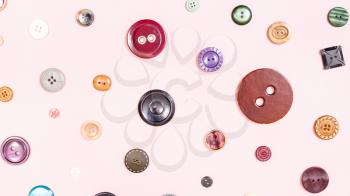 panoramic sewing background - top view of various buttons arranged on pink paper