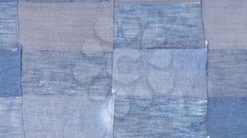 textile panoramic background - patchwork from many old blue denim flaps