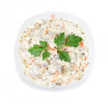 top view of portion of russian Olivier salad decorated by leaf of parsley in white bowl isolated on white background