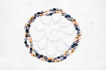 top view of hand crafted necklace from colored river pearls on gray concrete background