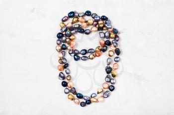 handmade necklace from various river pearls on gray concrete background