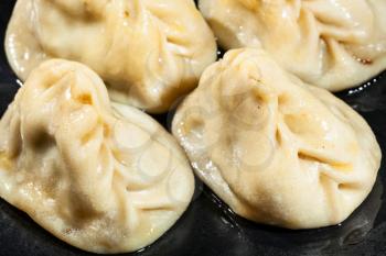 Manti (type of dumpling in turkic cuisine) oiled with butter close-up on black plate