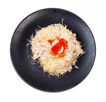 top view of portion of Quail Nest salad from ham, veal and beef tongue, grated cheese, dressed with mayonnaise and decorated by quail egg and salmon caviar on black plate isolated on white background