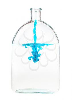 trickle of blue ink flow in water in glass flask isolated on white background