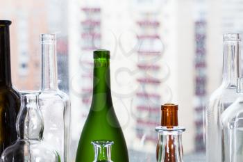 many empty bottles and view of apartment buildings through home window on background