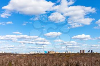 blue sky with white cumulus clouds over city park and residential district on sunny March day