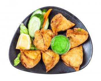 Indian cuisine - top view of portion of samosas (fried savoury pastry) on black plate isolated on white background